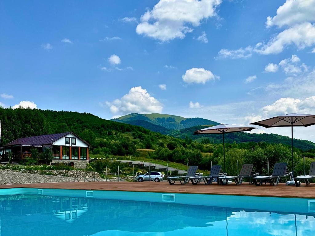 a swimming pool with chairs and umbrellas at Kolochava Eco Resort in Kolochava