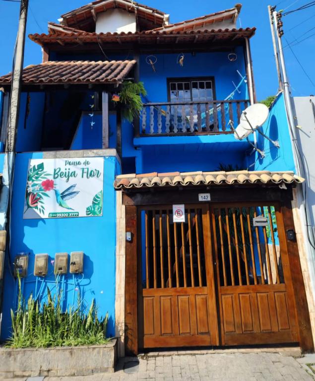 a blue house with a wooden door and a balcony at POUSO DO BEIJA FLOR in Paraty