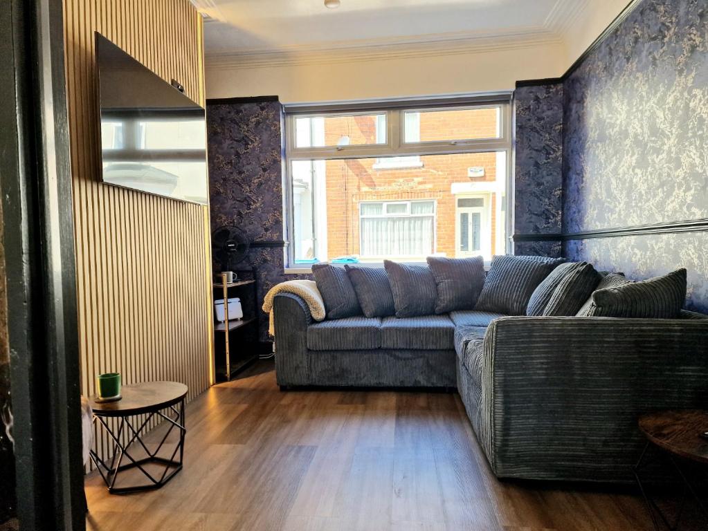 a living room with a couch and a large window at Super Stylish and Vibrant 3 Bed Getaway in Hull