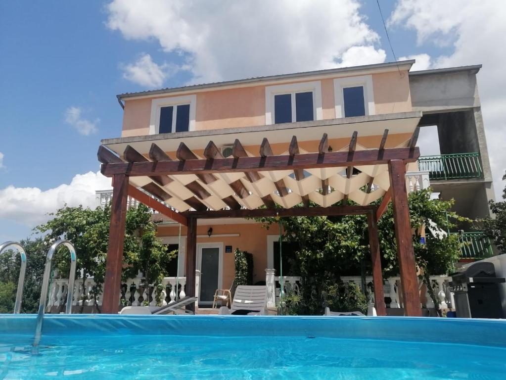 a villa with a swimming pool in front of a house at Bruna's apartment in Vrulje