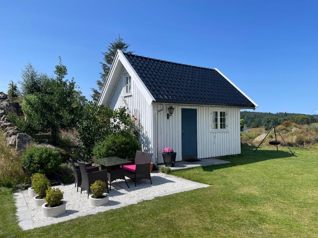 a white shed with a table and chairs in a yard at Villa Krågenes in Farsund