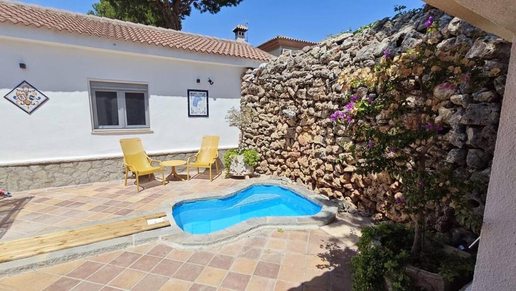 a patio with a table and chairs and a stone wall at 2-Person Studio, Private Splash Pool, 5 Min Beach in Novo Sancti Petri