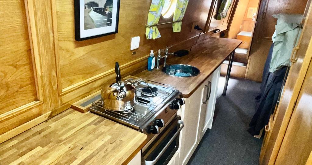 a tiny kitchen with a stove and a sink at Daisy Mutler Holiday Boat Hire in Bletchley
