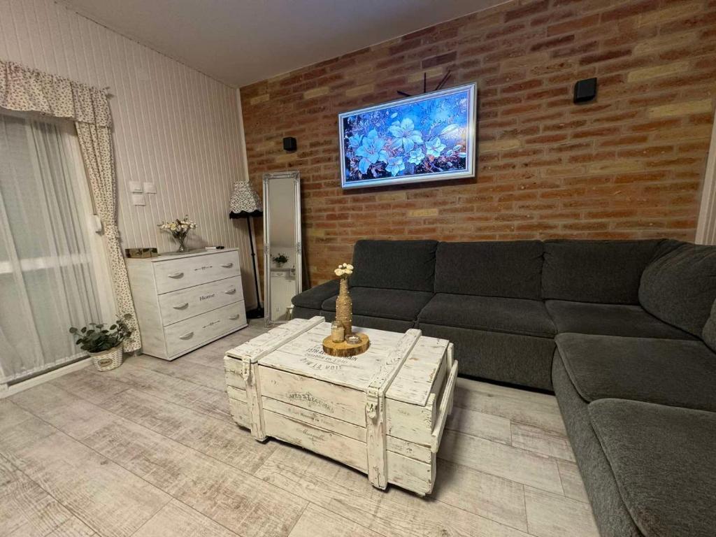 a living room with a couch and a brick wall at FYRED Vintage Apartman in Tiszafüred