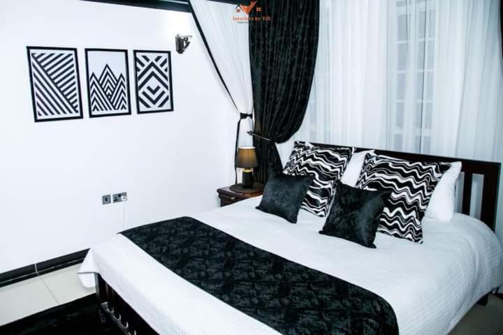 Un dormitorio con una cama con almohadas blancas y negras. en Roots Apart Hotel, en Nairobi