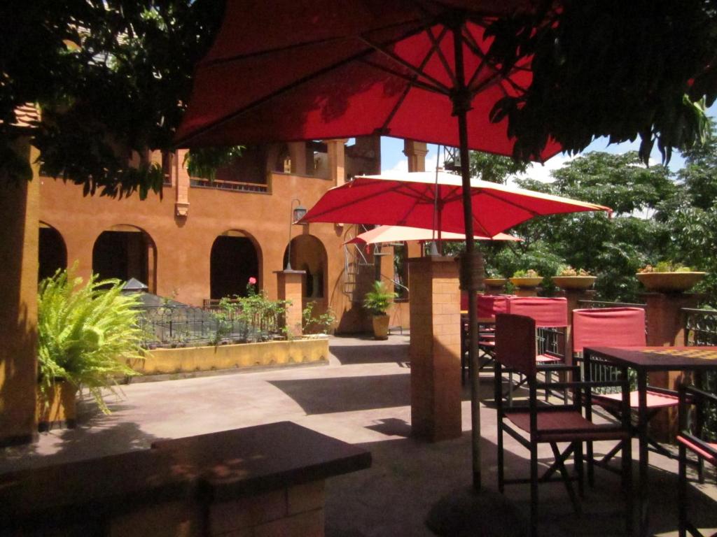 un patio con mesas y sillas y sombrillas rojas en Belvedere Hotel en Antananarivo