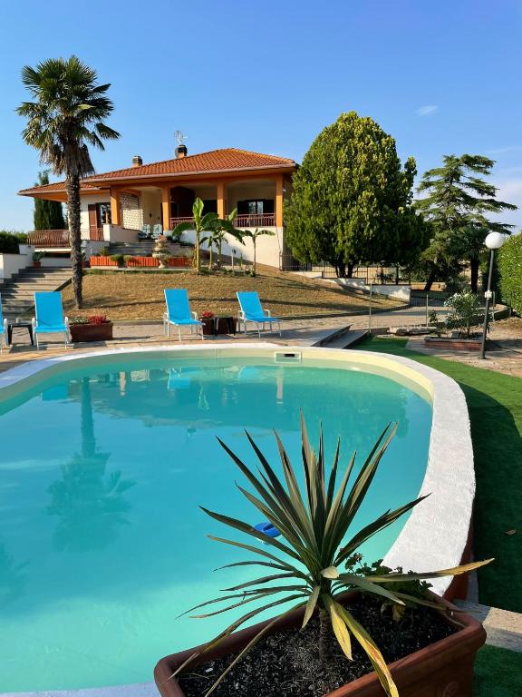 a swimming pool with chairs and a house in the background at Appartamento Pavone in Viterbo