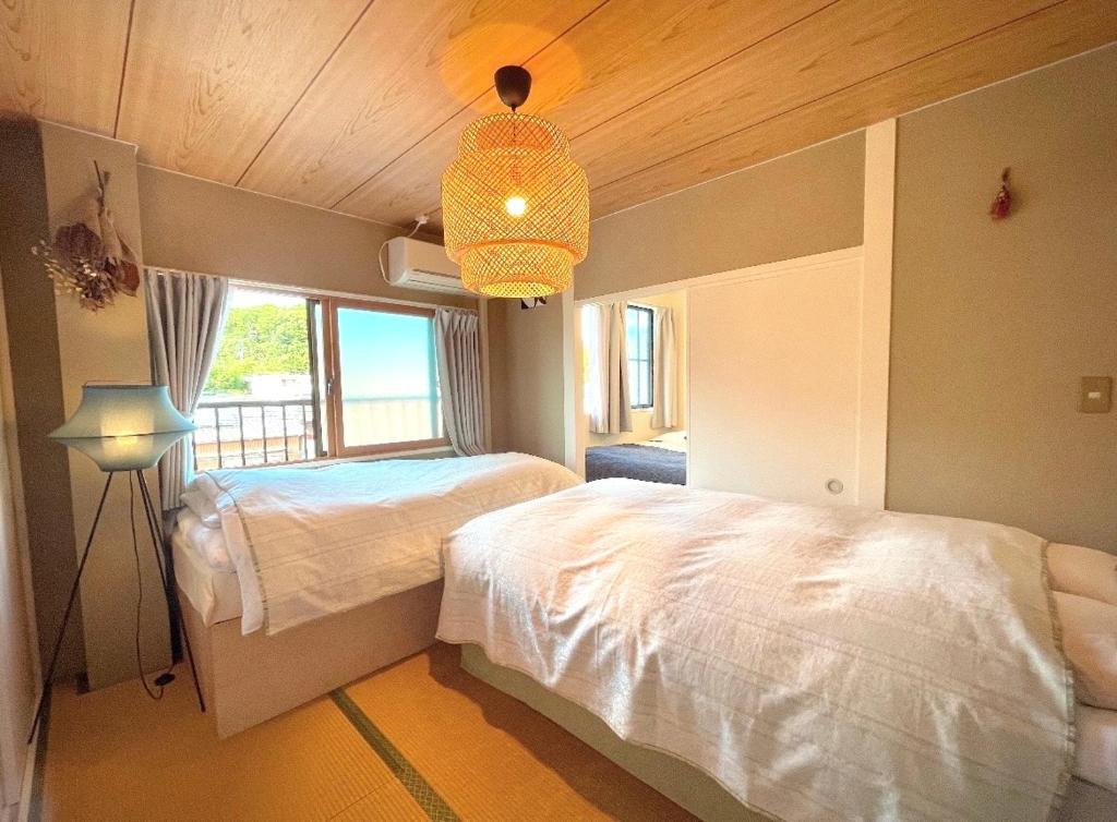 a bedroom with two beds and a chandelier at 伊勢神宮内宮前一民泊宿 i s e s h i m a 203一最大5名 in Ise