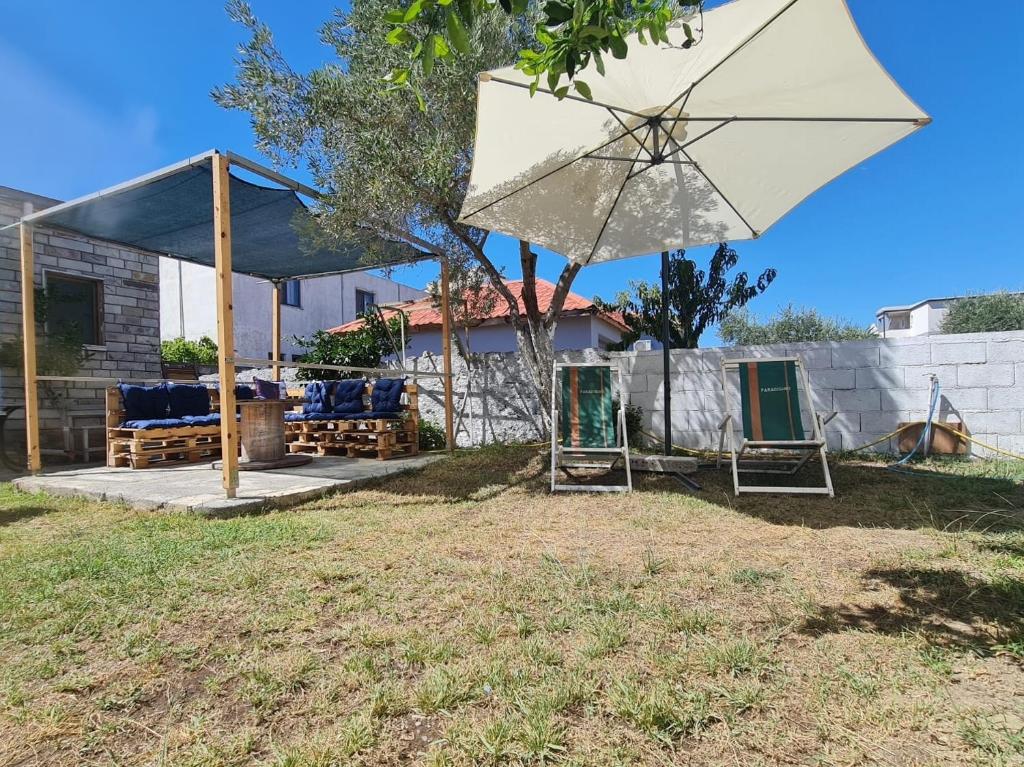 a patio with two chairs and an umbrella at Velipoja Home in Velipojë