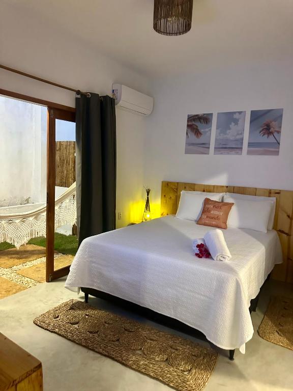 a bedroom with a large white bed and a window at Kza da Paty Preá dEla in Prea