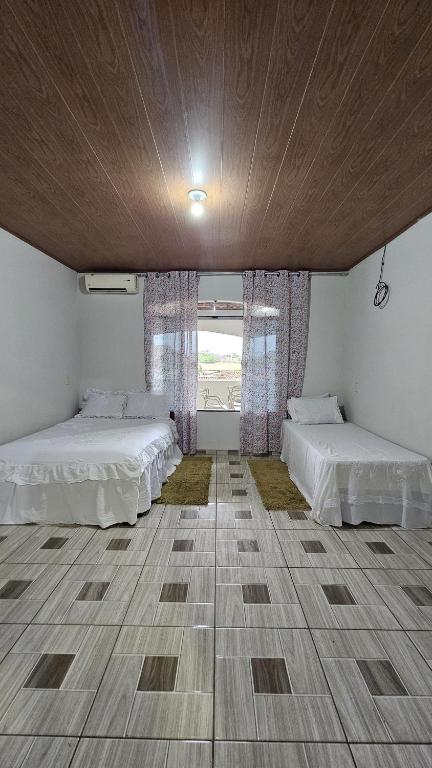 a large room with two beds and a window at Casa Amarela no Centro in Barreirinhas