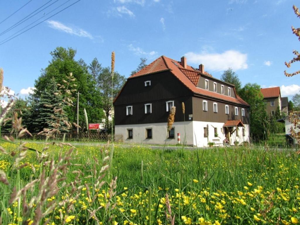 una casa con un tetto nero in un campo di Ferienwohnungen im Landstreicherhaus a Stolpen