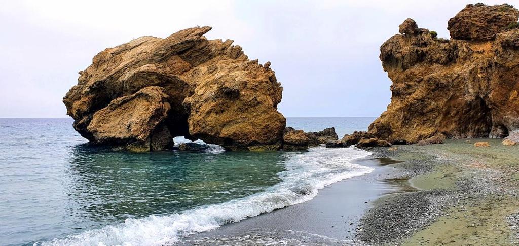 a beach with a large rock formation in the water at Polivios Apartment C in Térsa