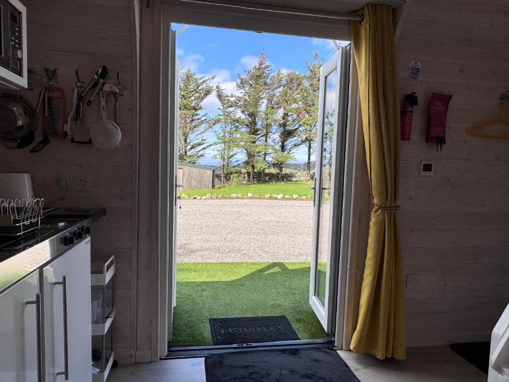 une cuisine avec une porte ouverte sur une cour dans l'établissement Coastal Cabin Oldshoremore, à Rhiconich