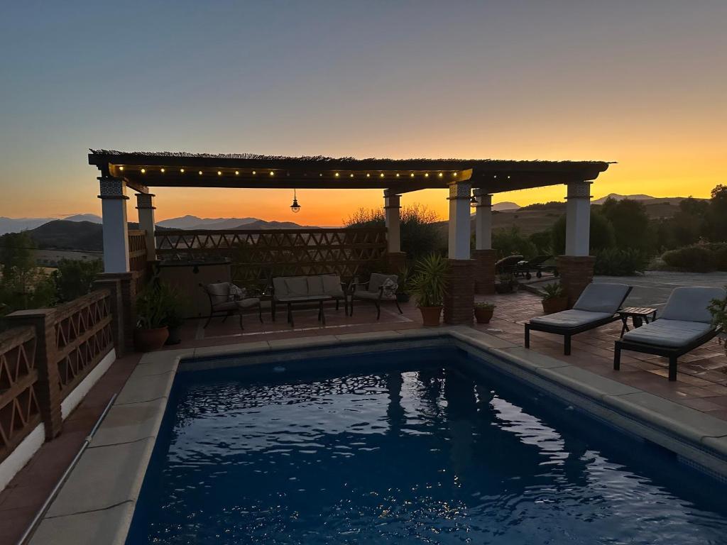a swimming pool with a pergola and a patio with chairs at Villa Azafran in Málaga