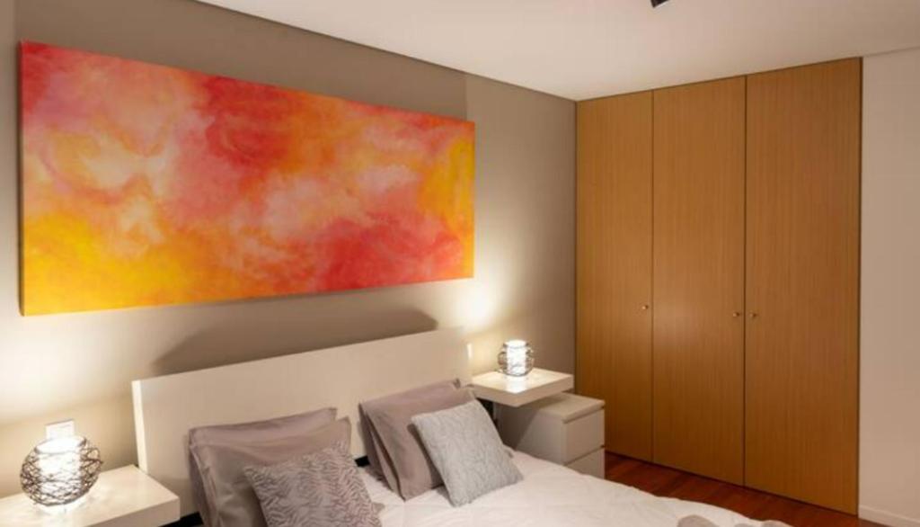 1 dormitorio con una gran pintura encima de una cama en Porto H Dragão, en Oporto