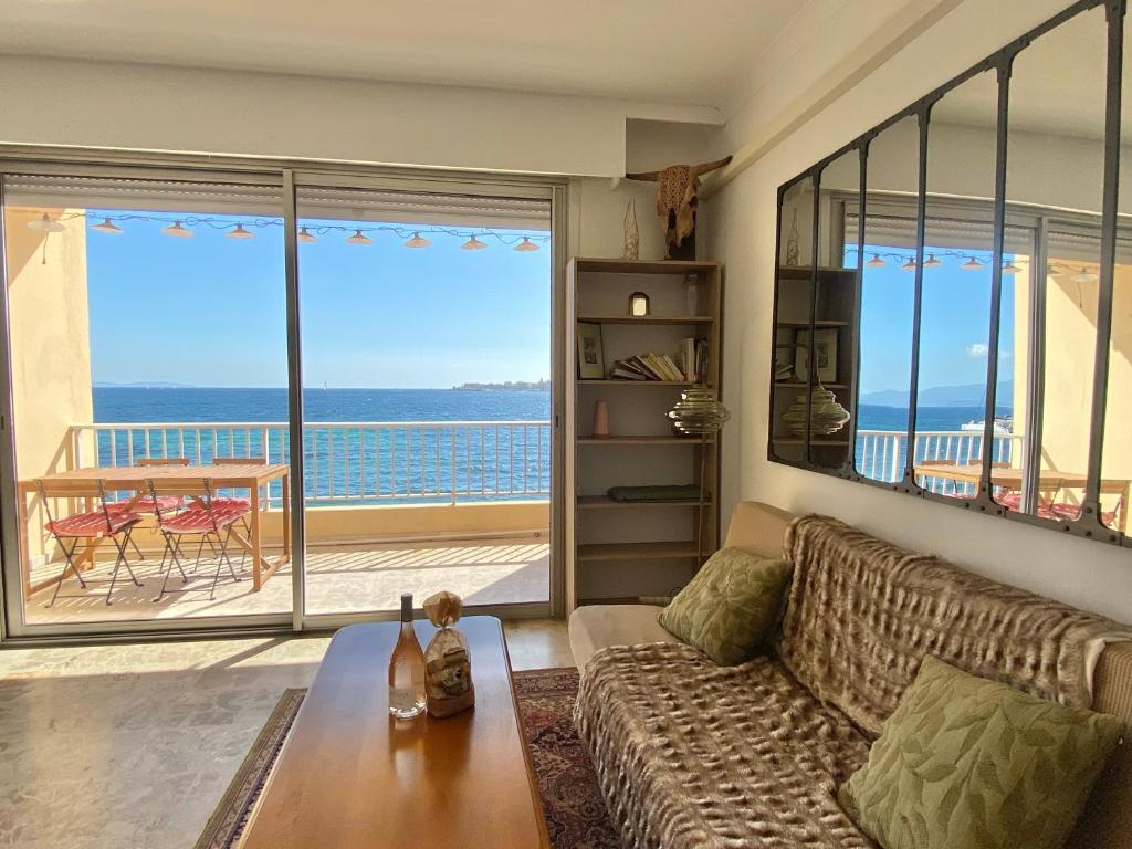een woonkamer met een bank en uitzicht op de oceaan bij Appartement pieds dans l eau in Ajaccio