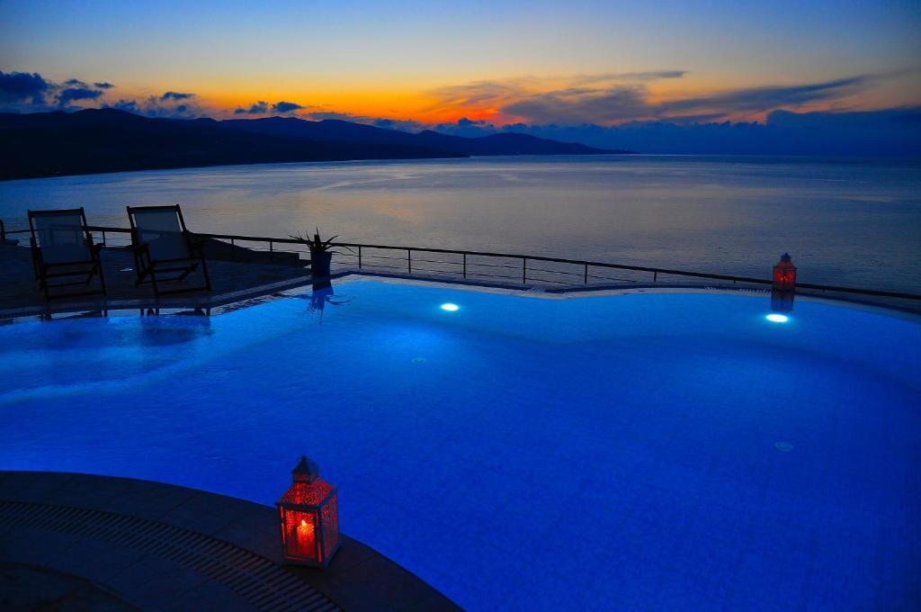 a large swimming pool with a sunset in the background at Pyrgos Zante Suites in Alikanas