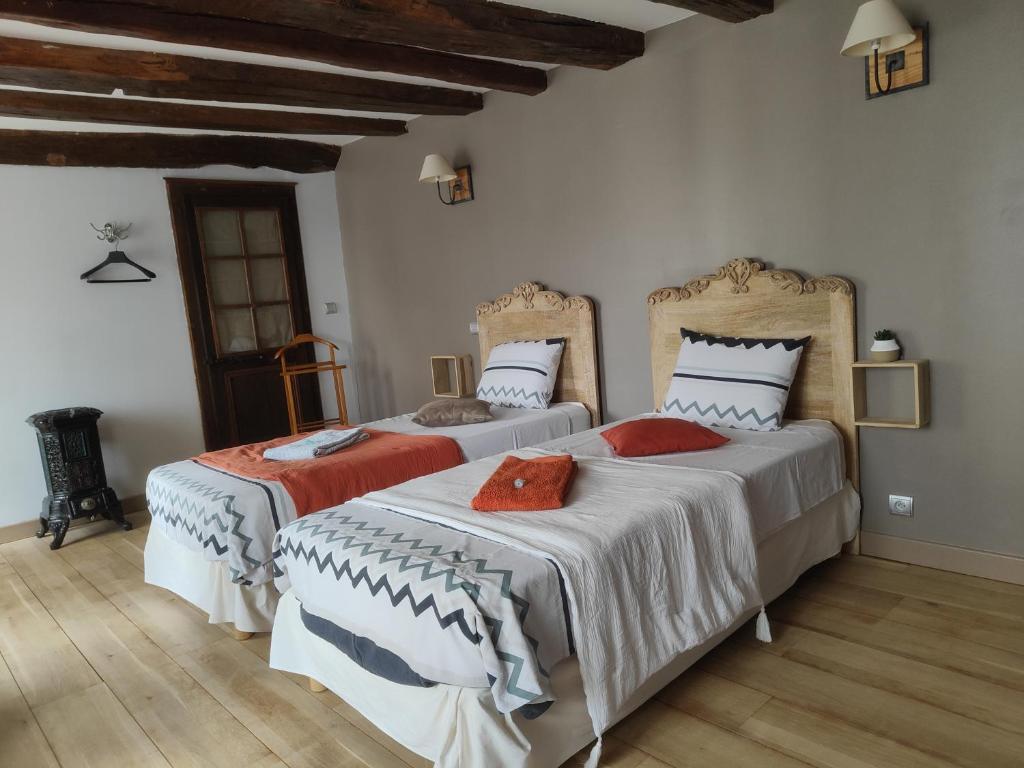 two beds in a room with white walls and wooden floors at La Mirabelle des 3 Forêts in Bricon