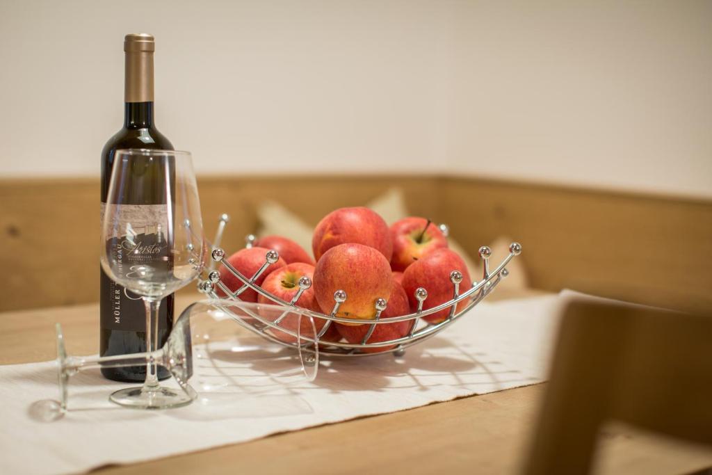 uma tigela de maçãs numa mesa com uma garrafa de vinho em Brugger Hof em Feldthurns
