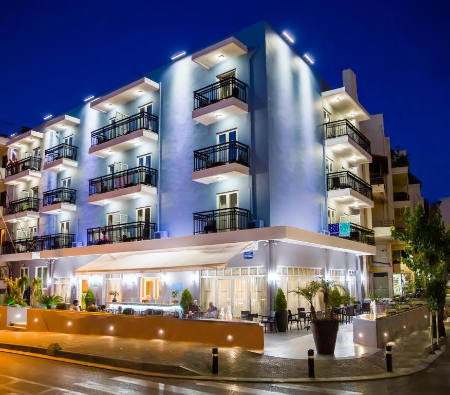 a large white building with balconies at night at Astali Hotel in Rethymno Town