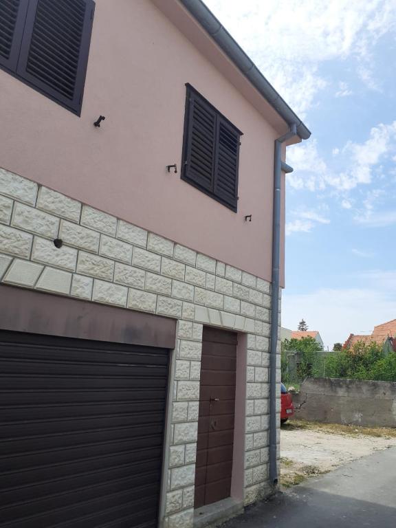a building with two garage doors and two windows at Apartman Juran in Murter