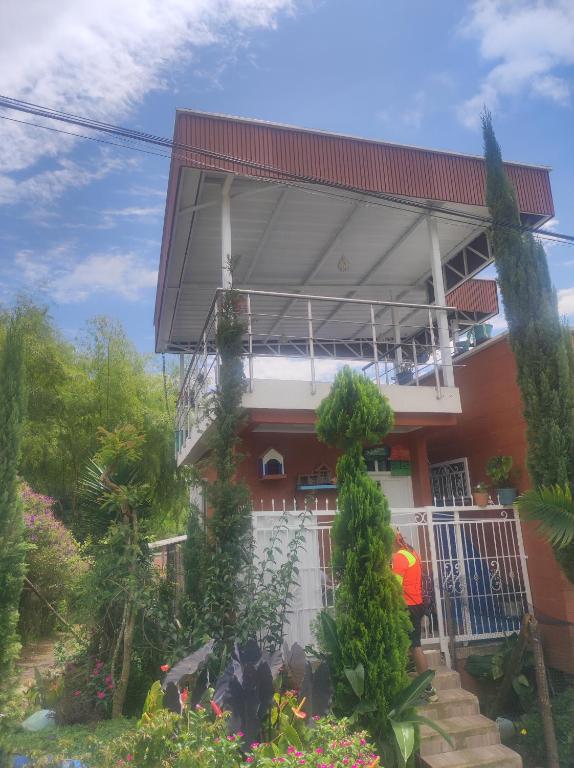 a house with a balcony and a man standing in front of it at Apartamento campestre guaduales en el estadio in Santa Rosa de Cabal