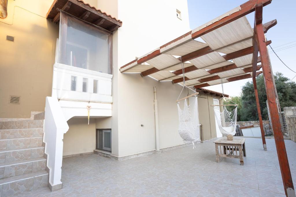 a patio with a wooden pergola next to a building at Sofia's seaview house in Platanias