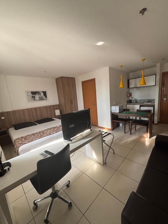a hotel room with a bed and a desk with a computer at Flat Aconchegante in Campos dos Goytacazes