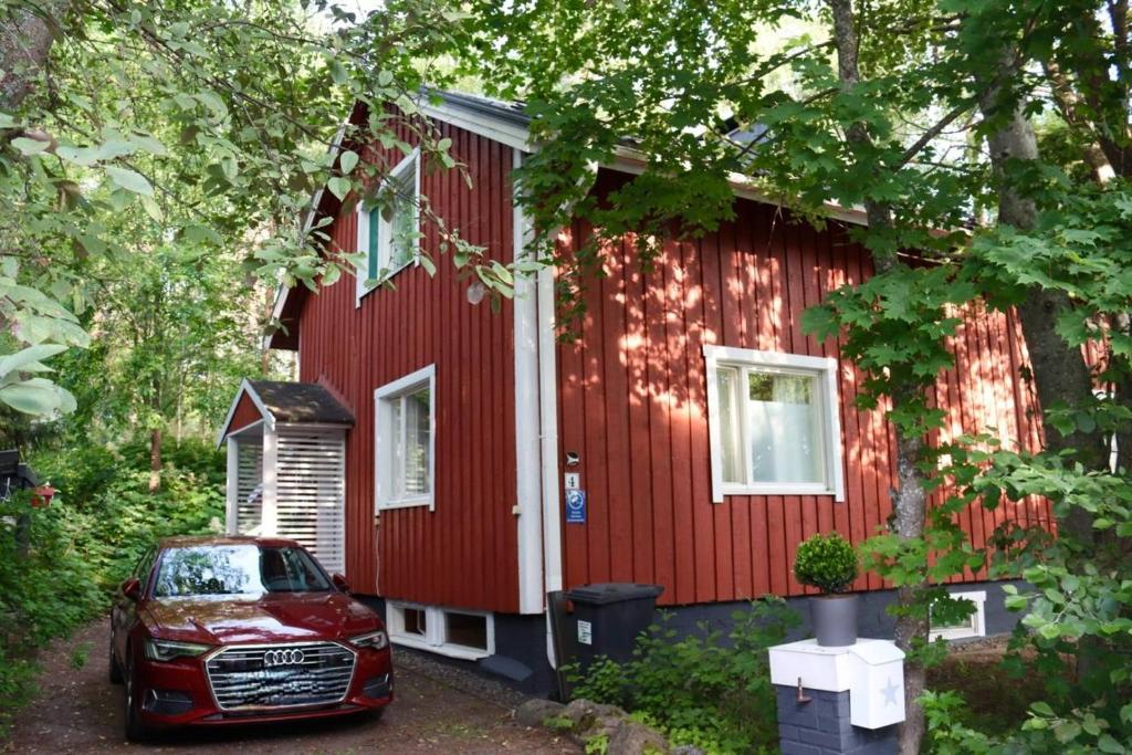 a red house with a car parked in front of it at The Red Residence, Savonlinna Centre in Savonlinna