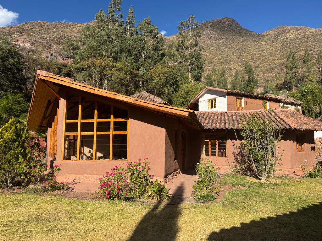 ein Haus auf einem Feld mit Bergen im Hintergrund in der Unterkunft Urquillos Wasi - Andean Cottage in Urubamba