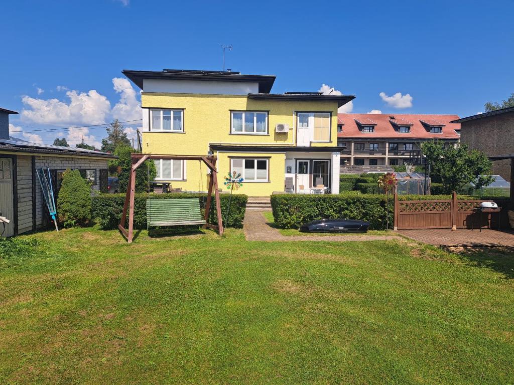 a yellow house with a bench in a yard at Kevade Apartement in Viljandi