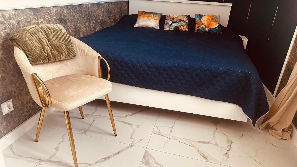 a bedroom with a bed and a chair at Apartament Azzurro - Old Town in Kłodzko
