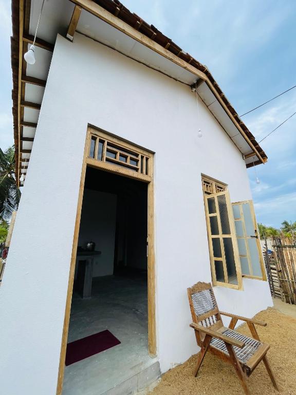 a white house with a chair in front of it at The luxy bay in Arugam Bay