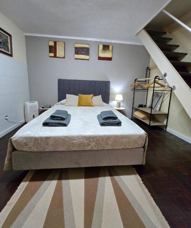 a bedroom with a large bed with a staircase at CASA RIBEIRINHO No Coração da Natureza in Ponta do Pargo