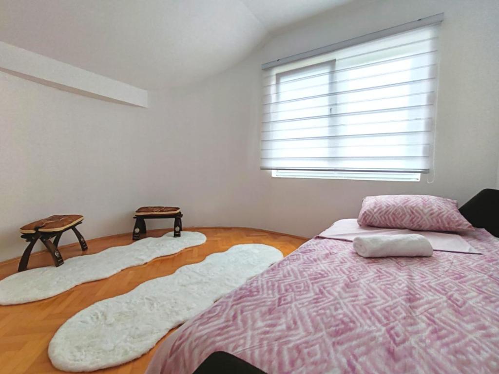 a bedroom with a bed and two rugs on the floor at Villa E&M in Srebrenik