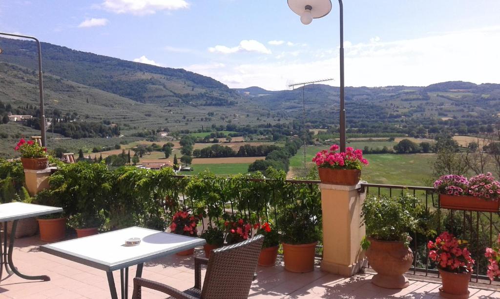 a patio with tables and chairs and a view of a valley at Albergo Il Cacciatore in Spello