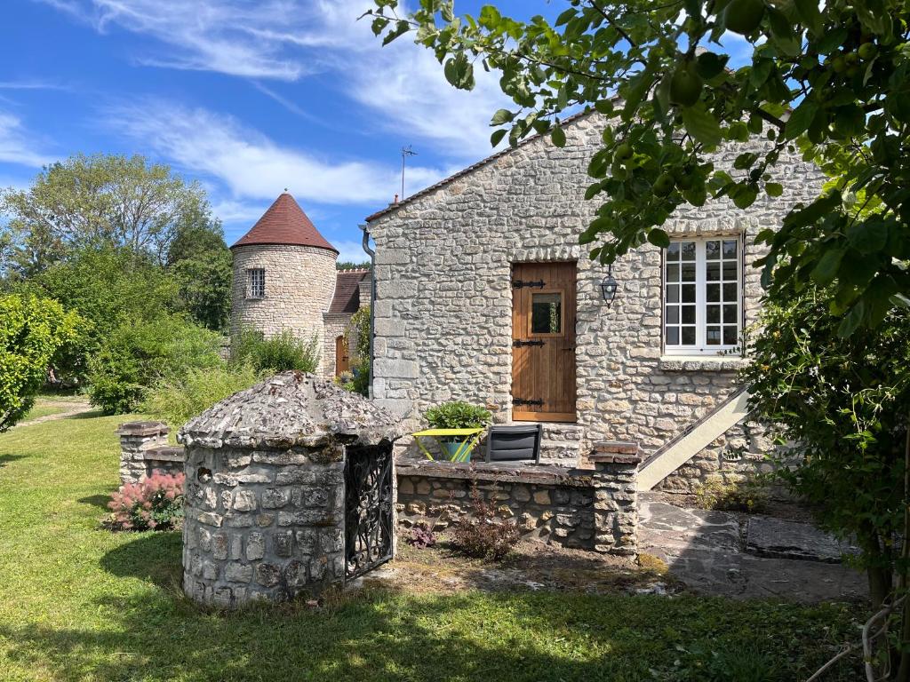 a stone house with a wooden door in a yard at La petite maison de Boisrival in Bury