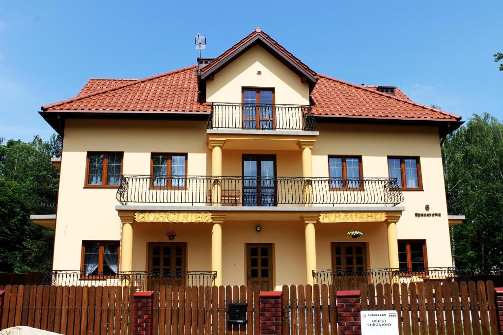 a large yellow house with a red roof at Gościniec Mazurski in Ruciane-Nida
