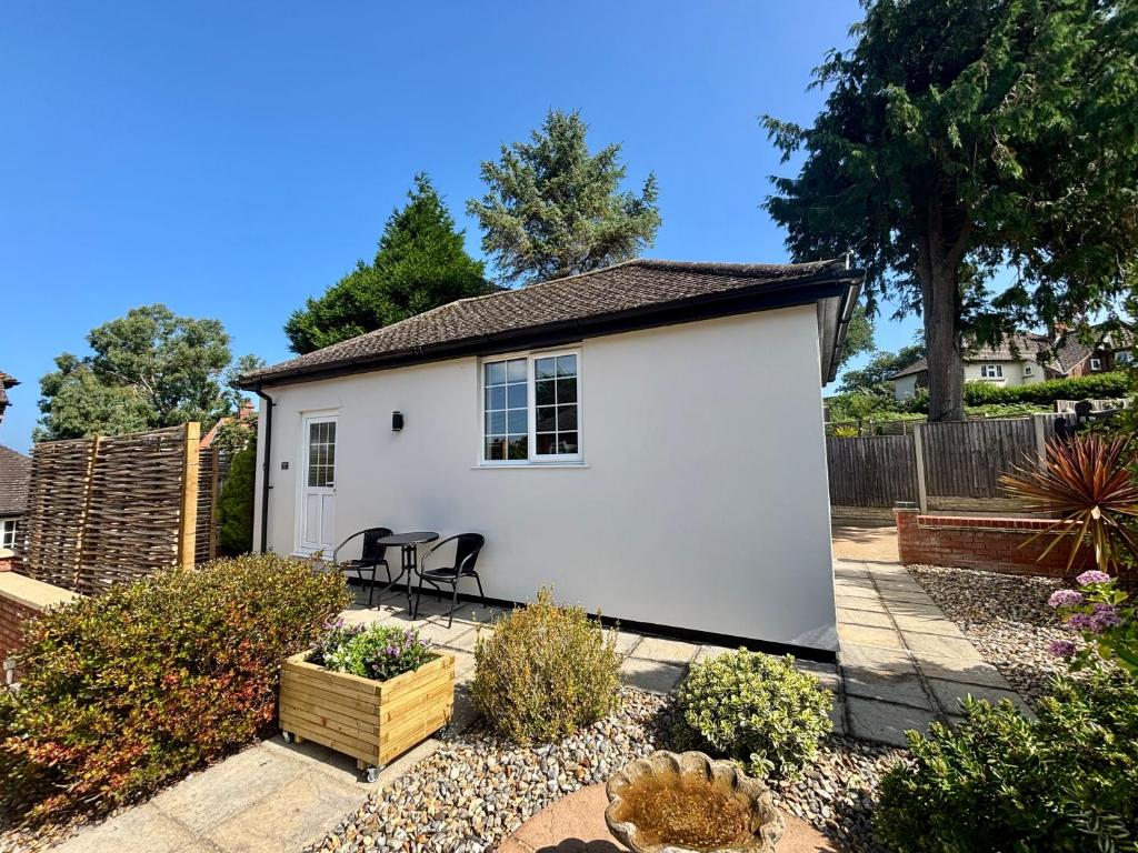 a white shed with a table and chairs in a yard at Seagulls Rest - Sheringham in Sheringham