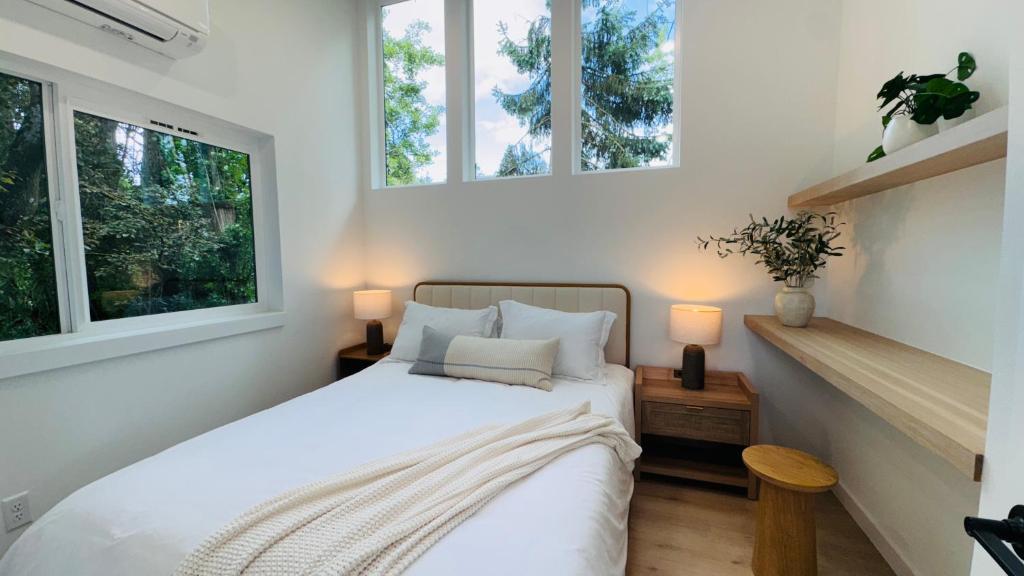 a bedroom with a white bed with two windows at Brand New Designer House 15min to downtown in Seattle