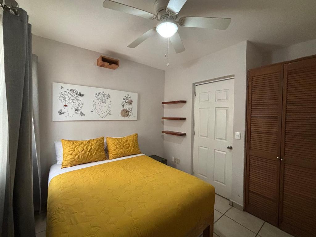 a bedroom with a yellow bed and a ceiling fan at Acogedor apartamento minimalista Mai in Puerto Vallarta