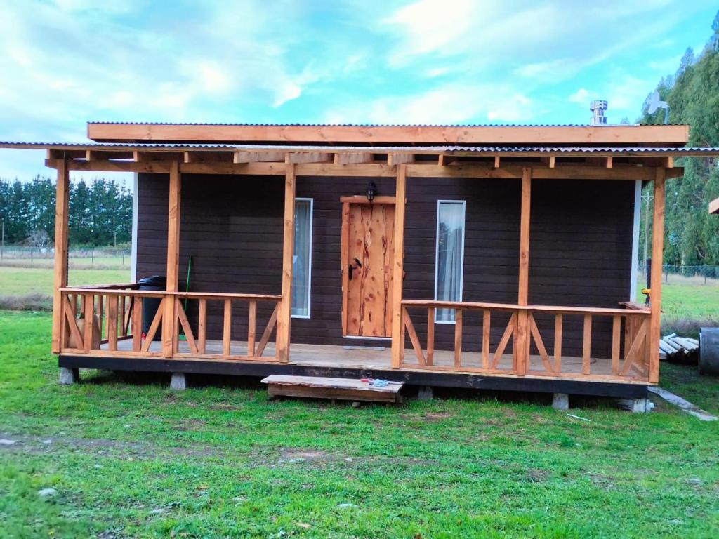 a large wooden cabin with a porch on a field at Cabañas Los Tatas in Puerto Octay