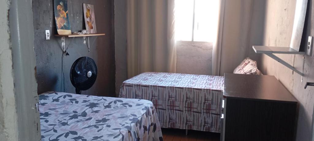 a room with two beds and a table and a window at Casa do Betto in Aracaju