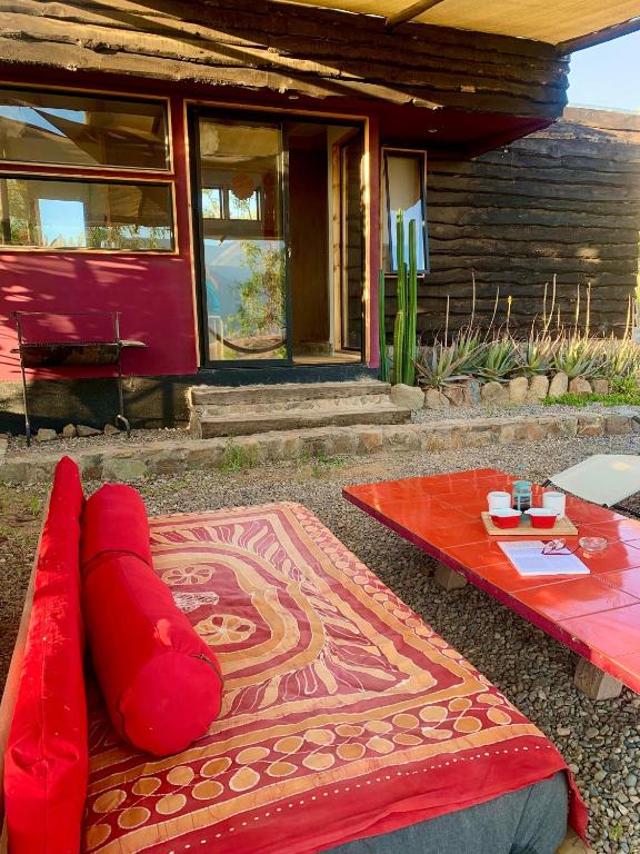 a red couch and a table in front of a house at Santuario Cosmico Mamalluca in Vicuña