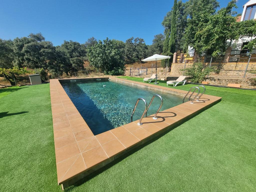 a swimming pool in a yard with a green lawn at Corteganillas in Cortegana