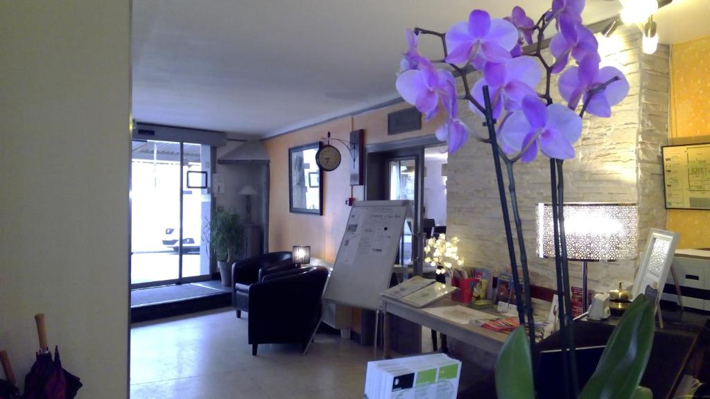 - un salon avec un vase orné de fleurs violettes dans l'établissement Hotel De La Bastide, à Carcassonne