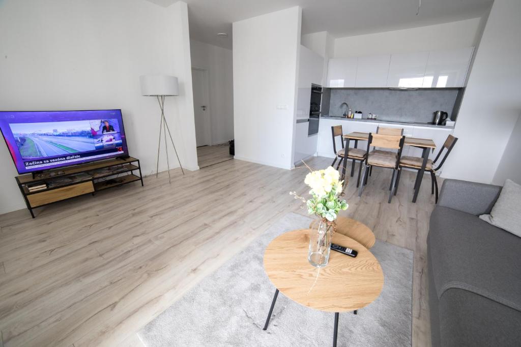 ein Wohnzimmer mit einem Sofa und einem Tisch mit Blumen darauf in der Unterkunft Stylish Poprad Stay - 10min to High Tatras & Parking in Poprad