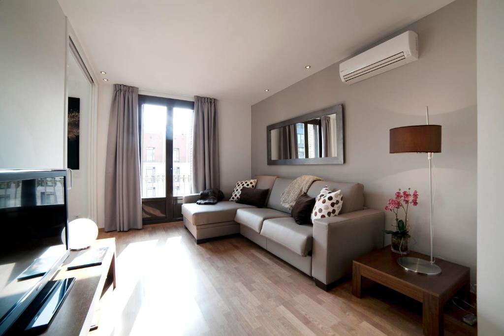 een woonkamer met een bank en een tv bij Serennia Apartamentos Ramblas - Plaça Catalunya in Barcelona