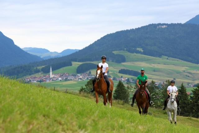 three people riding horses on a grassy hill at Ca' Santina in Stoccareddo